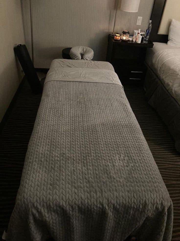 Massage table with a knit blanket, face cradle, candle and massage oils ready for a session
