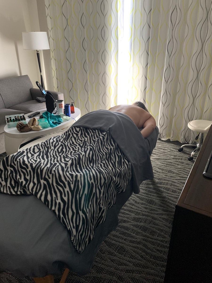 Client relaxing face down on the massage table with essential oils set out beside it