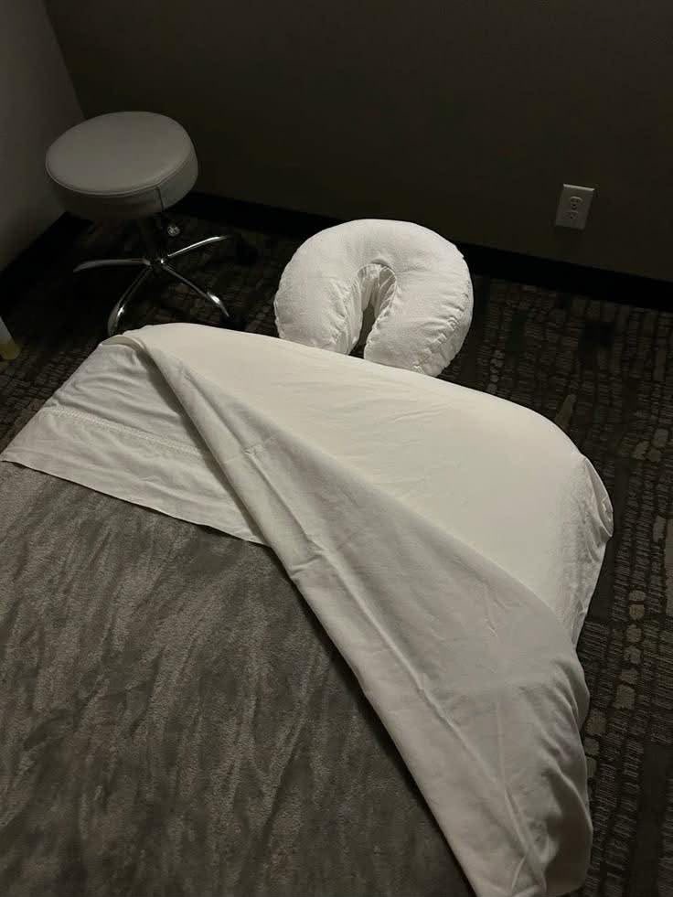 Massage table dressed with a white sheet and face cradle before a treatment