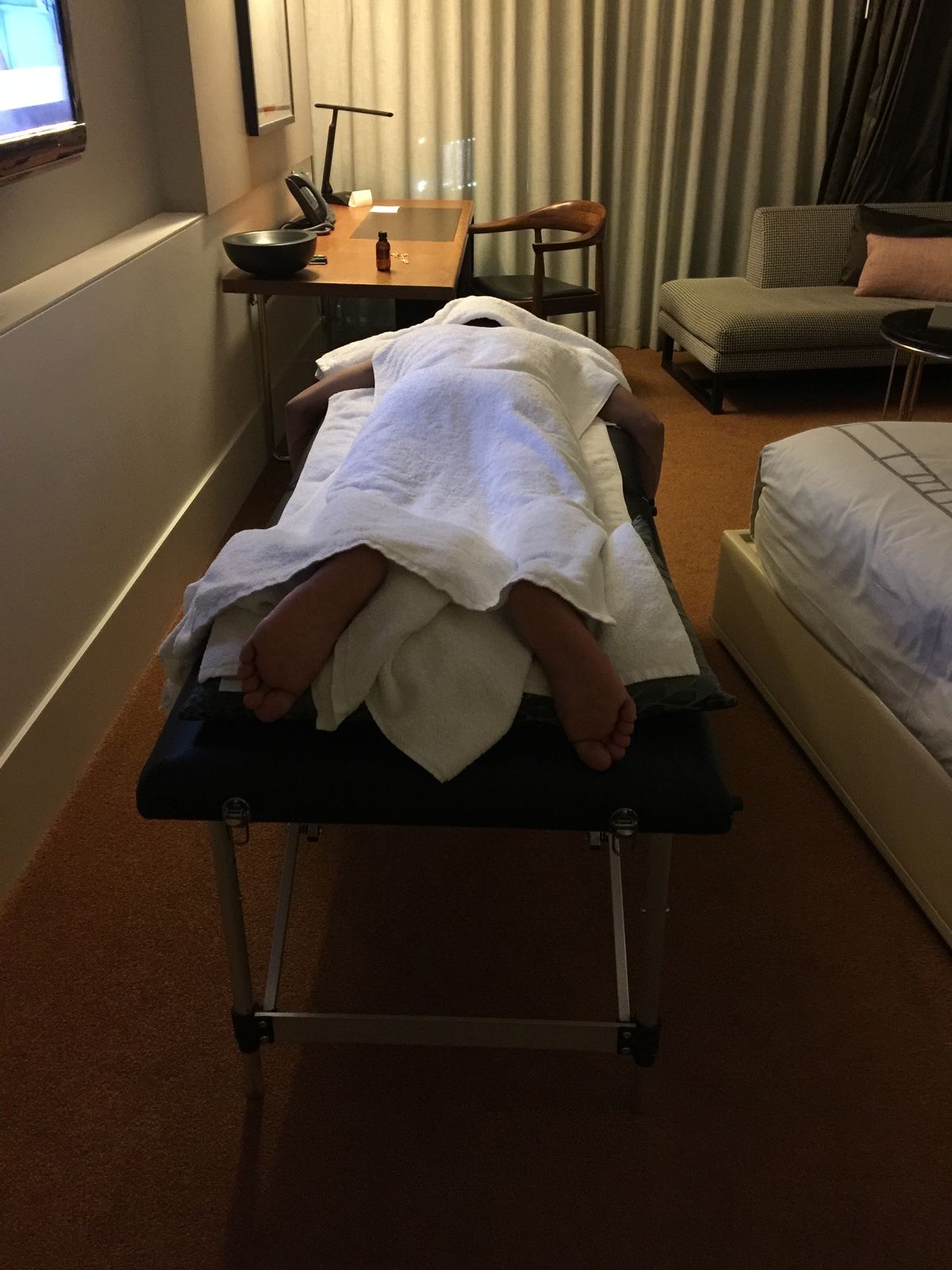 Client covered in white towels on a massage table during a full body session